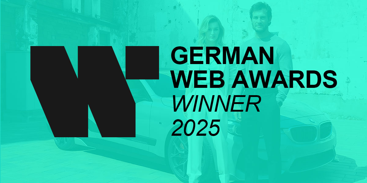 Zwei Personen stehen vor einem weißen Auto, darüber das Logo der German Web Awards und der Text 'WINNER 2025'